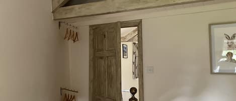 A staircase with wooden beams and a white railing, leading to a room with a door and a framed picture on the wall.