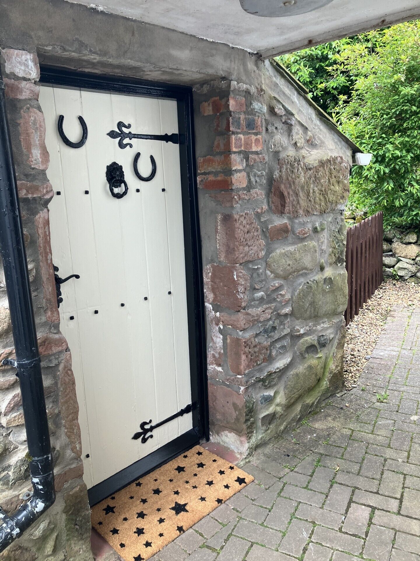 Una puerta blanca con manijas de metal negro y un felpudo con estampado de estrellas en la entrada.