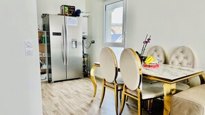 Una cocina moderna con refrigerador empotrado, una mesa de comedor con cuatro sillas y un ventanal que proporciona luz natural.