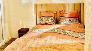 Un dormitorio con cama, almohadas y mesita de noche.
