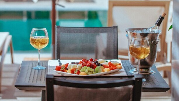 Une table avec une assiette de fruits, un verre de vin et une bouteille de champagne.