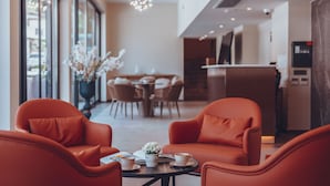 Un intérieur moderne avec des fauteuils en cuir, une table sur laquelle se trouvent une tasse et un livre, et un coin repas à l’arrière-plan.