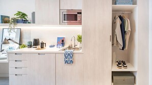Eine moderne Küche mit integriertem Mikrowellenherd, Spüle mit Handtuch und Ablagefläche mit Schuhen und Kleidung.