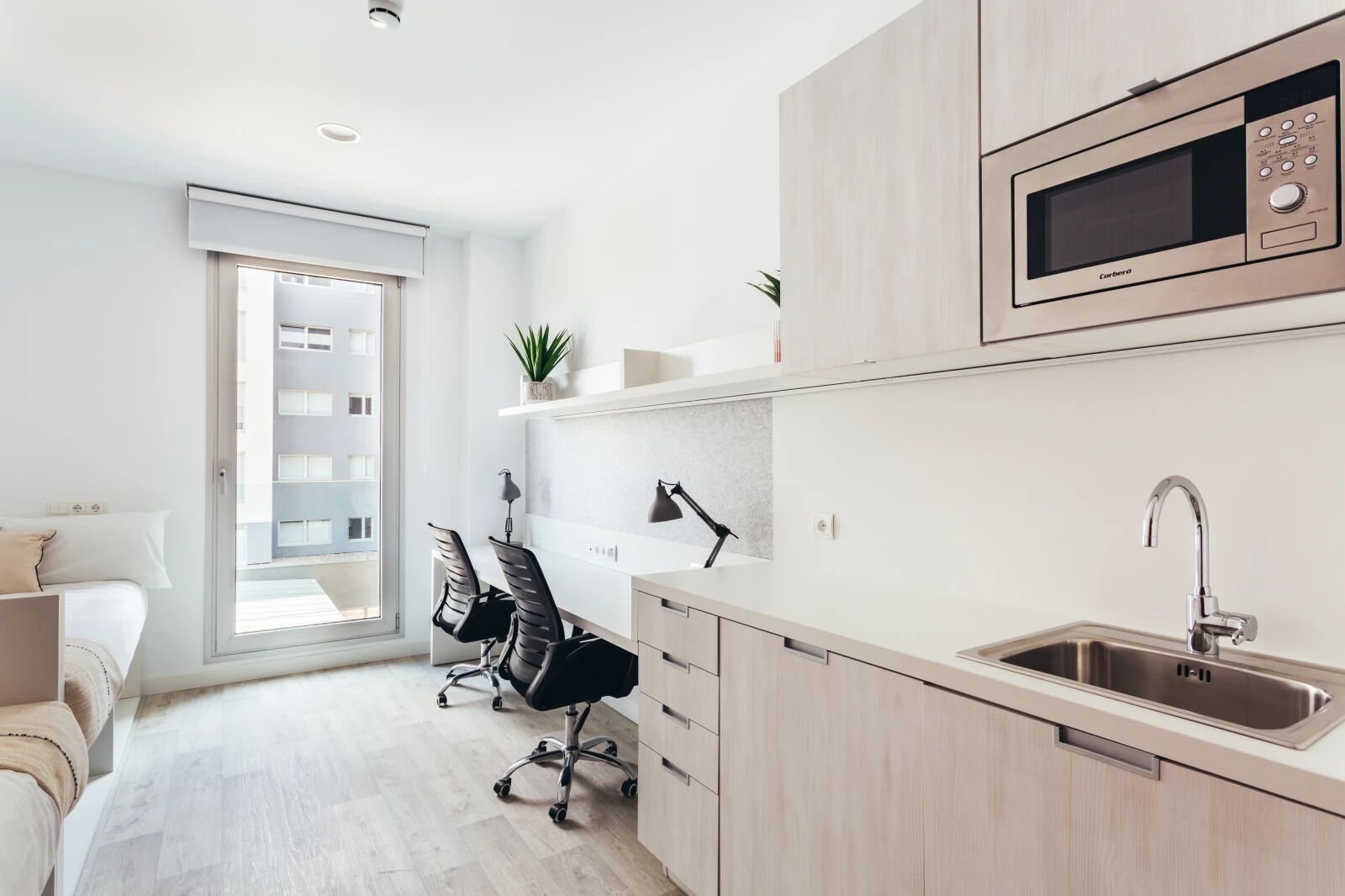 A modern kitchen with a microwave, sink, and two office chairs.