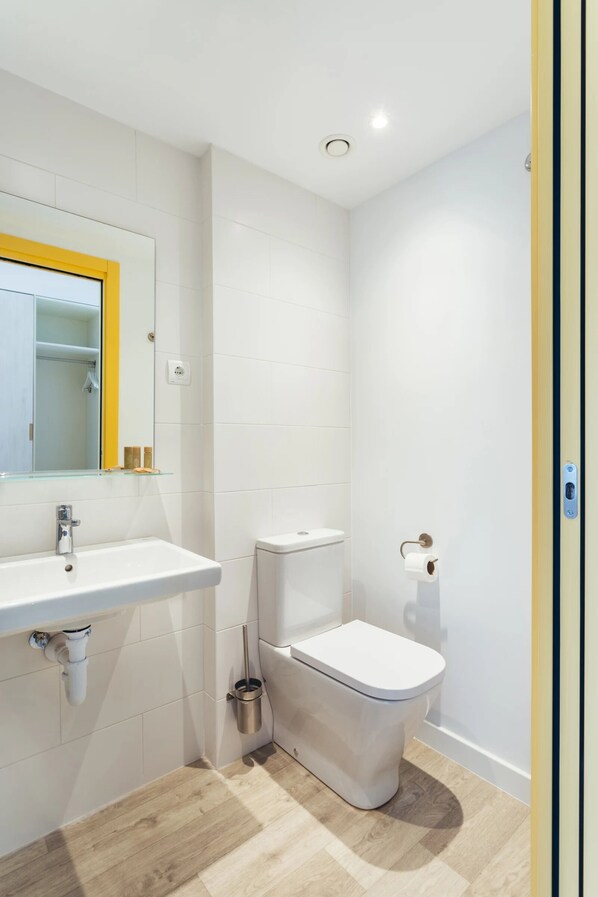 A bathroom with a white sink, toilet, and mirror.