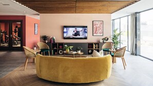 Ein modernes Wohnzimmer mit einem gelben Sofa, Holzboden und großen Fenstern.