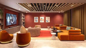 Ein modernes Wohnzimmer mit einem Ecksofa, Poufs und einem Flachbildfernseher.