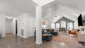 A spacious living room with a large sectional sofa, a dining area with a table and chairs, and a ceiling fan. - Cozy Carolina Trace 3BR w/ Relaxing Golf Course Views - Deck & Fire Table (Sanford)