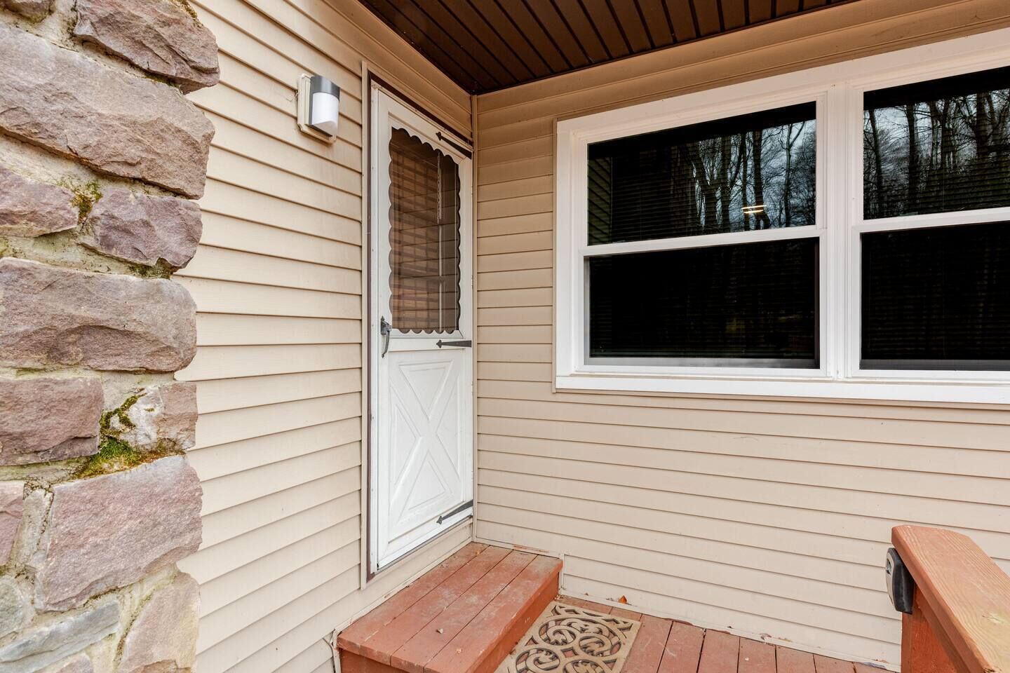 A house with a stone exterior, a white door, and a window with blinds.