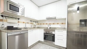 A modern kitchen with white cabinets, stainless steel appliances, a dishwasher, a microwave, an oven, and a refrigerator.