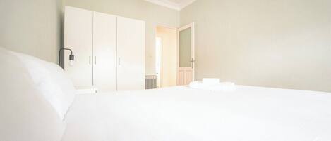 Een slaapkamer met een groot bed, een kledingkast en een spiegel.