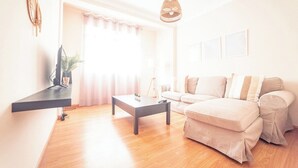 Sala de estar com sofá, mesa de centro e televisão sobre um móvel.