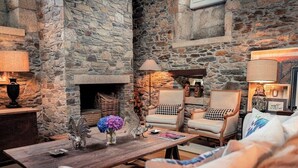 A cozy room with stone walls, a fireplace, two armchairs, and a wooden coffee table. - Villa Los Magnolios "Paderne" (Paderne)