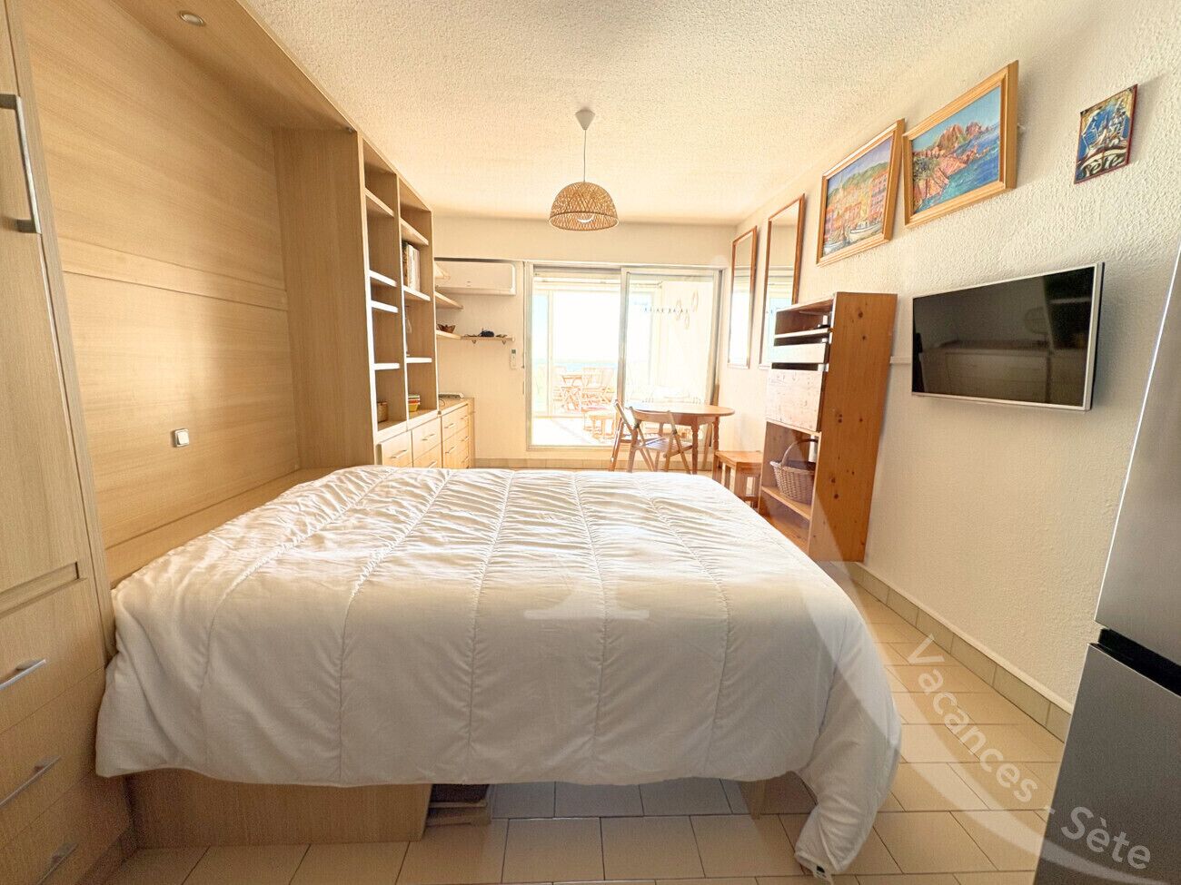 Une chambre à coucher avec un lit, une armoire en bois et un téléviseur fixé au mur.
