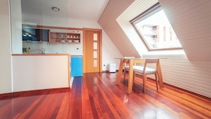 Une cuisine moderne avec un plancher en bois, un coin repas comprenant une table et des chaises, et une lucarne.