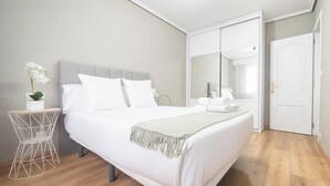 A modern bedroom with a bed, a bedside table with a plant, a mirror, and a wardrobe.