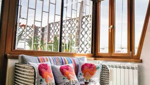 A cozy room with a view through a window, a radiator, and a sofa with colorful pillows. - Chic and Spacious Rome Penthouse (Roma)