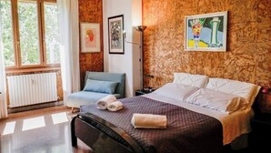 A bedroom with a bed, a chair, a radiator, and a window. - Chic and Spacious Rome Penthouse (Roma)