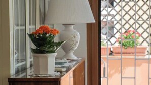 A window with a potted plant and a lamp on a wooden table. - Chic and Spacious Rome Penthouse (Roma)