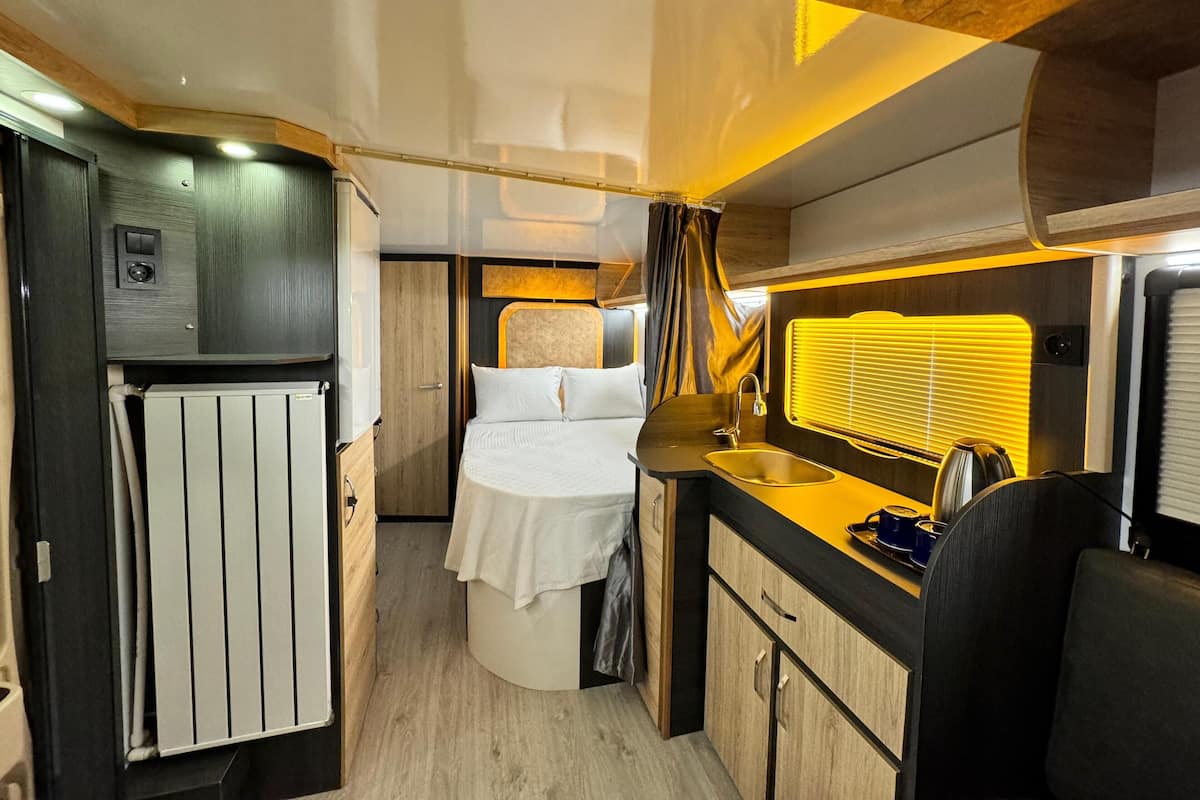 Ein kompaktes Wohnmobil-Interieur mit Kochnische, Bett und Bad.