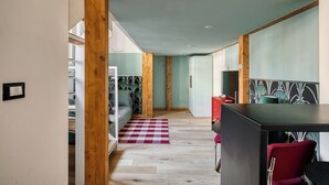 Uma cozinha moderna com vigas de madeira, um espaço de refeições com uma cadeira vermelha e um tapete quadriculado.