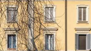 A building with multiple windows, a central entrance, and two parked cars. - The Green; Luxury Loft in the center of Milan (Milano)