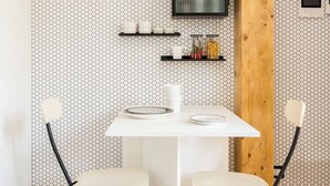 A compact dining area with a white table and two chairs, a wooden beam, and a hexagonal patterned wall. - The Green; Luxury Loft in the center of Milan (Milano)