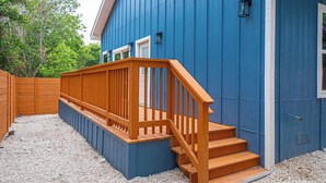 A blue building with a wooden deck and steps leading to a white door.