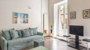 A living room with a sofa, a coffee table, a TV, and artwork on the walls. - MetaM Apartment in the City Center by Wonderful Italy (Palermo)