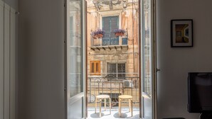 A room with a glass door leading to a balcony with two stools and a small table. - MetaM Apartment in the City Center by Wonderful Italy (Palermo)