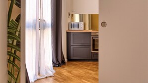 Una cocina con un microondas sobre una encimera de madera, un armario gris y una planta en la esquina.