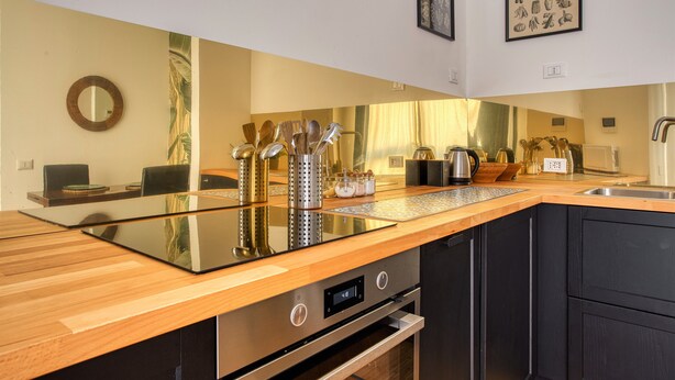Cocina moderna con encimera de madera, electrodomésticos de acero inoxidable y una placa vitrocerámica integrada.