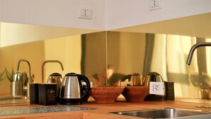 Una encimera de cocina con cafetera, teteras y cuencos de madera.