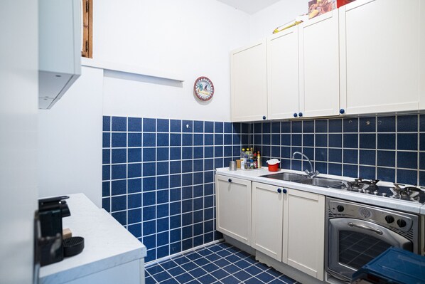 Een koelkast, een oven, kookgerei, borden en bestek, eettafels