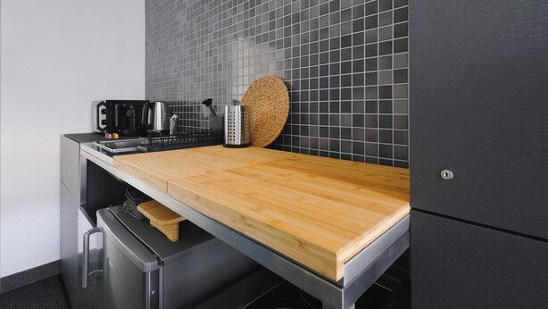 Een moderne keuken met een houten aanrechtblad, roestvrijstalen apparatuur en een zwart betegelde achterwand.