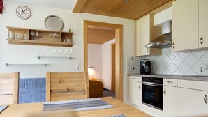 Een keuken met houten kastjes, een koffiezetapparaat en een eettafel met stoelen.
