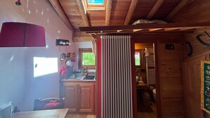 Une cuisine de taille réduite avec des poutres en bois, une fenêtre et un meuble rouge.