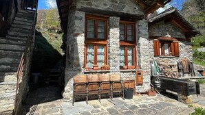 Une maison en pierre avec des poutres en bois, un escalier en pierre et une terrasse en pierre.