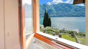 Ein Zimmer mit großem Fenster mit Blick auf einen See und Berge.
