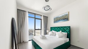 Una habitación de hotel moderna con una cama grande, vistas a la ciudad y un candelabro.