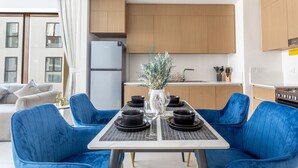 A modern kitchen with wooden cabinets, a white countertop, and a dining area with a table set for four.