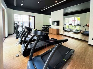 Une salle de sport équipée de tapis de course, d’un téléviseur et d’un miroir.