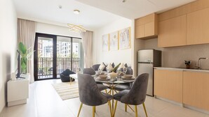 Una cocina moderna con armarios de madera, refrigerador empotrado y comedor con mesa de vidrio y sillas grises.
