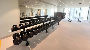 A gym with rows of dumbbells, a large mirror, and exercise equipment.