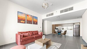 A modern living room with a red sofa, a white coffee table, and a dining area with chairs.