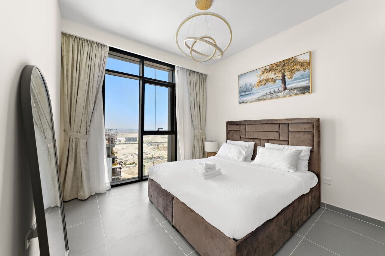 Ein Hotelzimmer mit einem großen Bett, Blick auf die Stadt und einem Gemälde an der Wand.