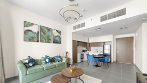 Ein modernes Wohnzimmer mit einem grünen Sofa, einem runden Couchtisch und Kunstwerken an der Wand.