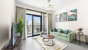Ein modernes Wohnzimmer mit einem Flachbildfernseher, einem runden Couchtisch, einem grünen Sofa und Blick auf die Stadt durch große Fenster.