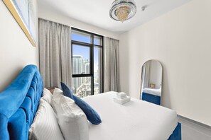 Ein Hotelzimmer mit einem großen Bett, Blick auf die Stadt, einer Kristallleuchter und einem Spiegel an der Wand.