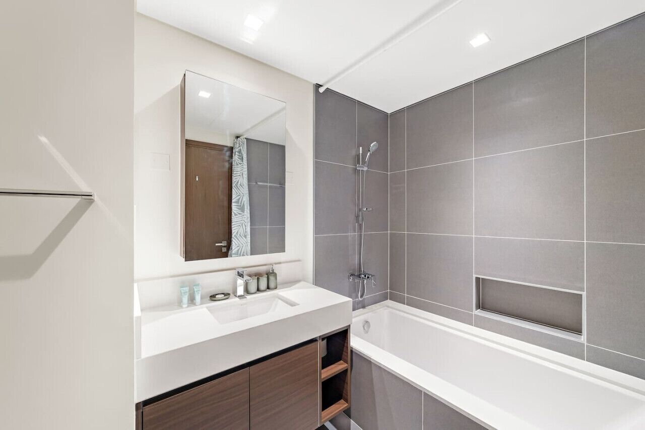 Une salle de bain moderne avec un lavabo blanc, un miroir et une douche.
